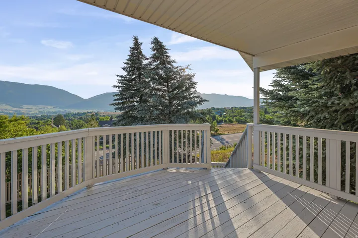 Spacious exterior deck with white painted railings and a sheltered overhead structure