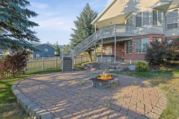 Paved patio featuring a stone fire pit, bordered by a retaining wall