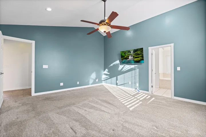 Carpeted room featuring a vaulted ceiling with a ceiling fan, recessed lighting, and teal-painted walls