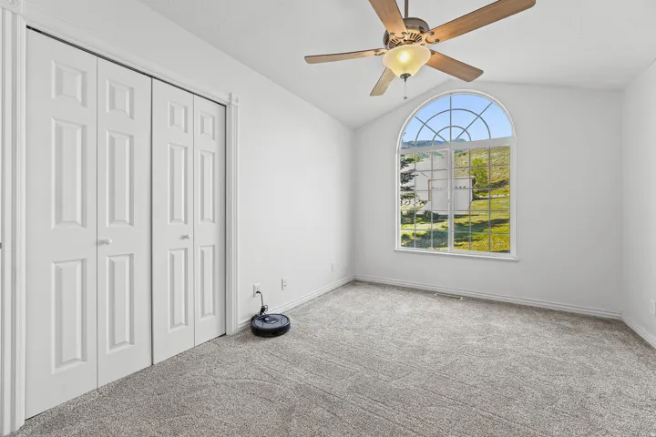 Arched window with grilles providing natural light, accompanied by neutral carpeting and white walls