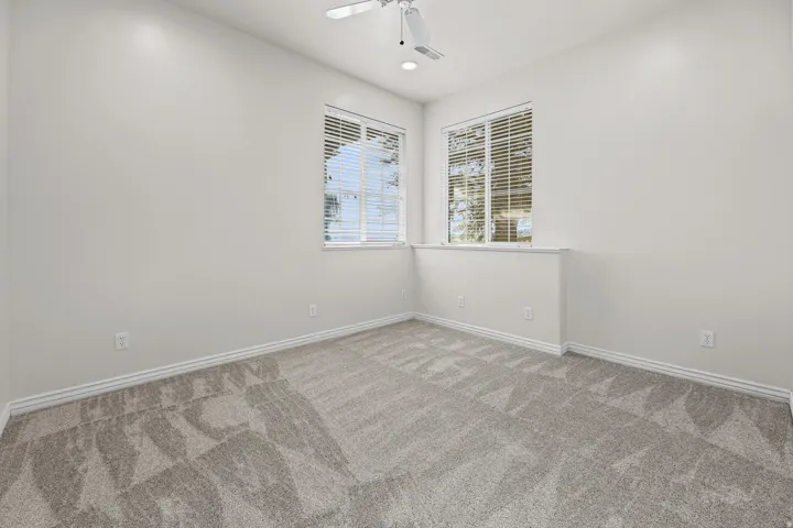 Carpeted room with a ceiling fan, recessed lighting, and two windows featuring blinds