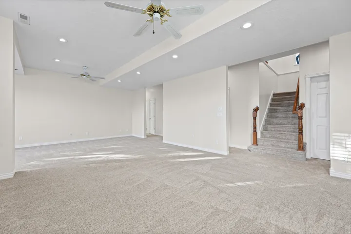 Spacious carpeted room featuring recessed lighting and two ceiling fans