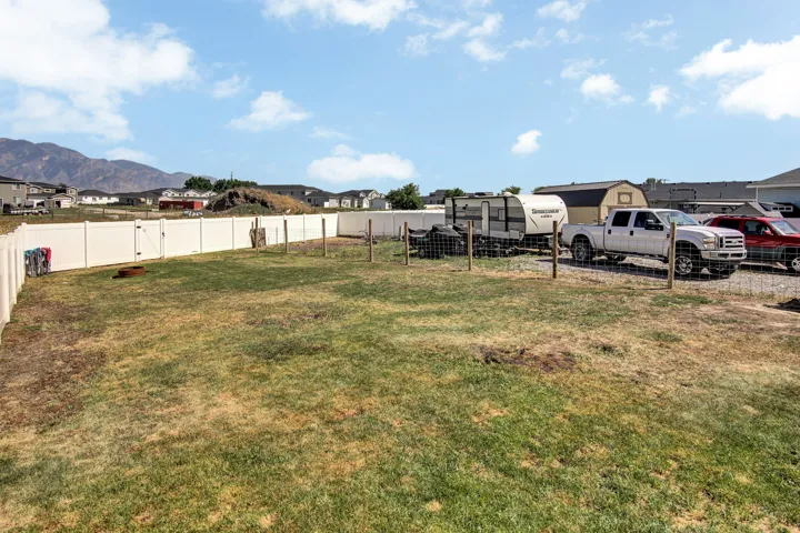 Expansive backyard with privacy fencing, a gate, and a storage shed