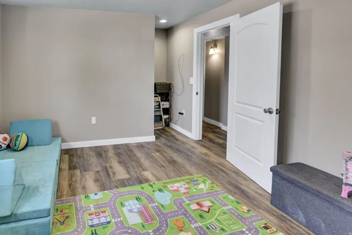 Interior space featuring wood-finish flooring, light-colored walls, white baseboards, and a white interior door with a paneled design