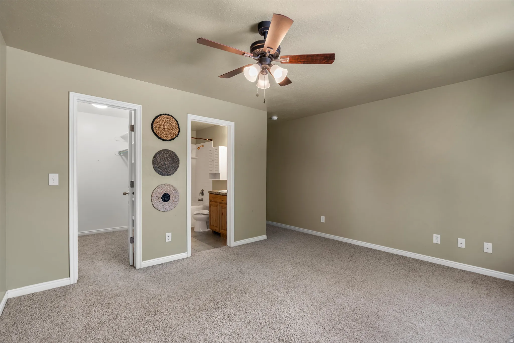 Carpeted room featuring a ceiling fan with integrated lighting, neutral wall tones, and white baseboards