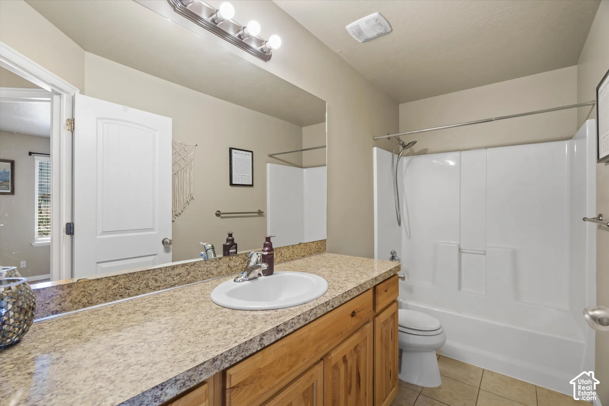 Full bathroom featuring a single vanity with a solid surface countertop, an undermount sink, and wood-finish cabinetry