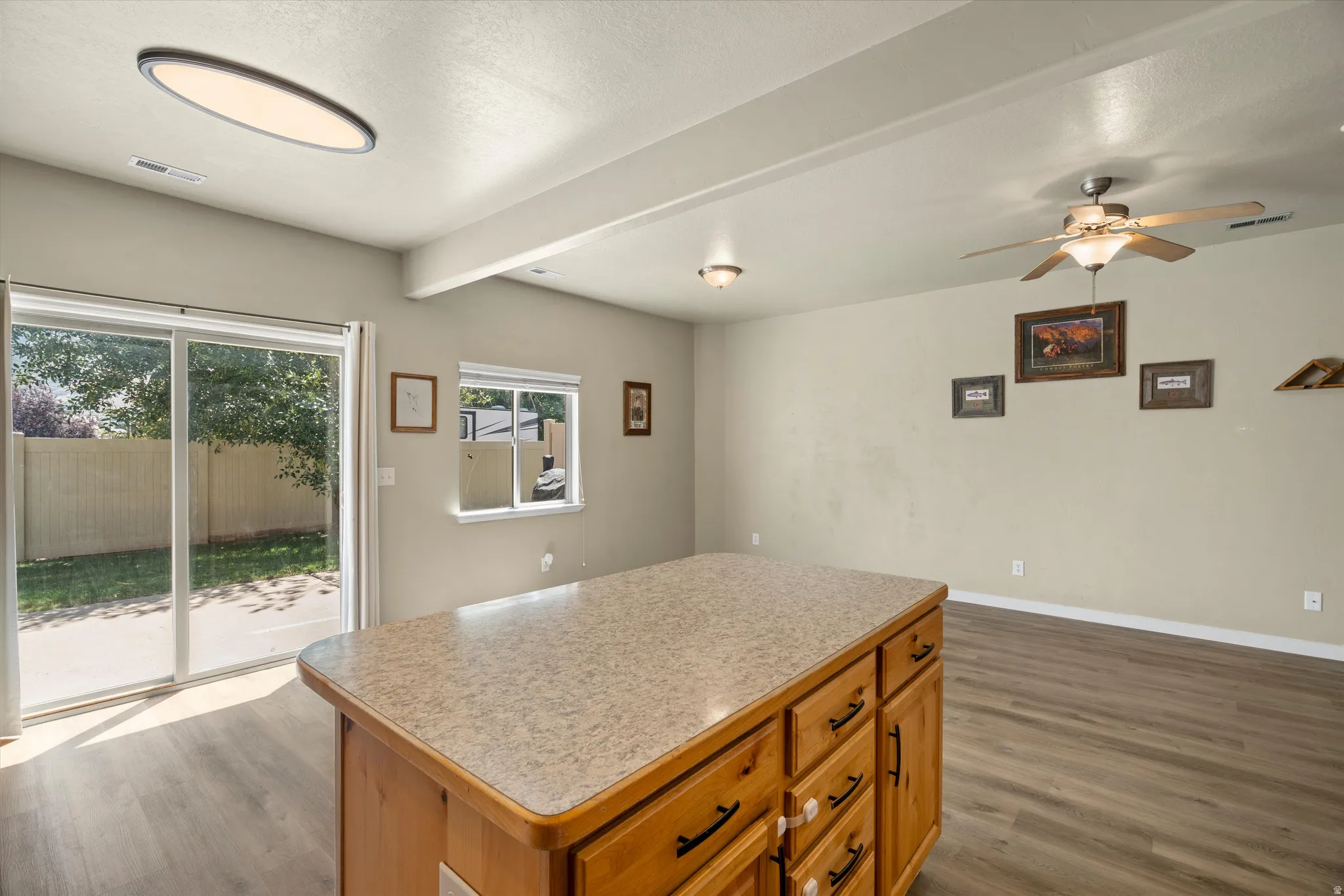 Kitchen island with a laminate countertop, wood-finish cabinetry, and black hardware