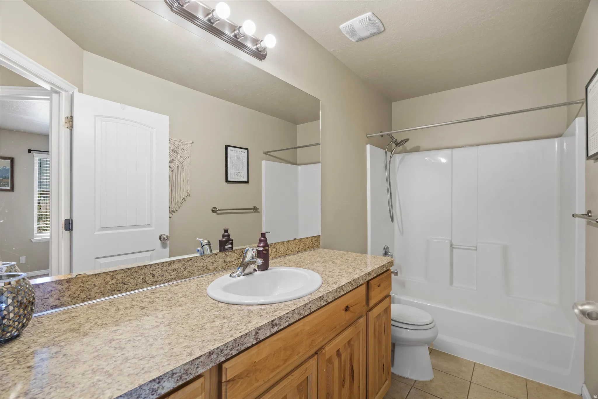 Full bathroom featuring a single vanity with a solid surface countertop, an undermount sink, and wood-finish cabinetry