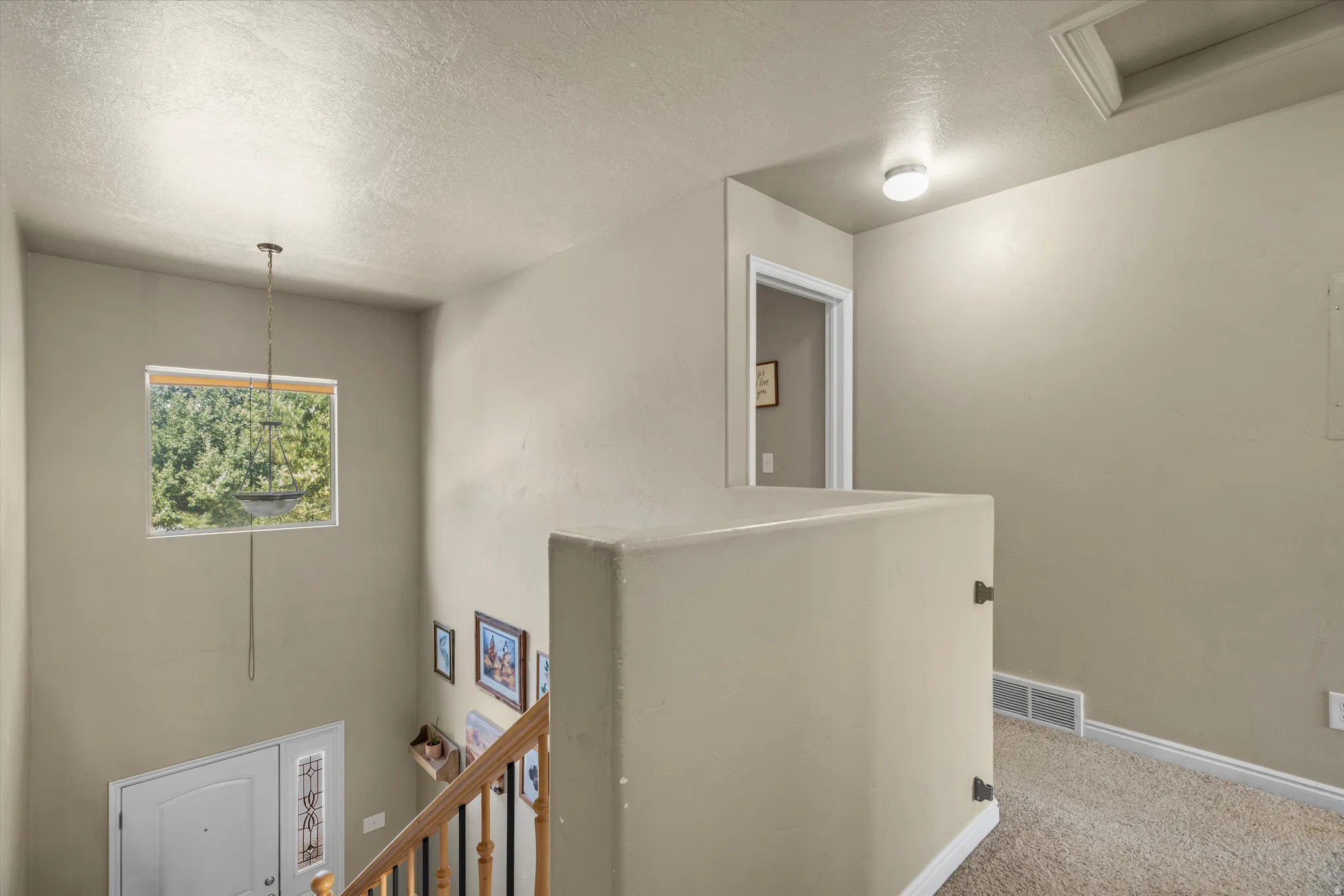 Two-story entryway featuring a decorative light fixture and a window with natural light