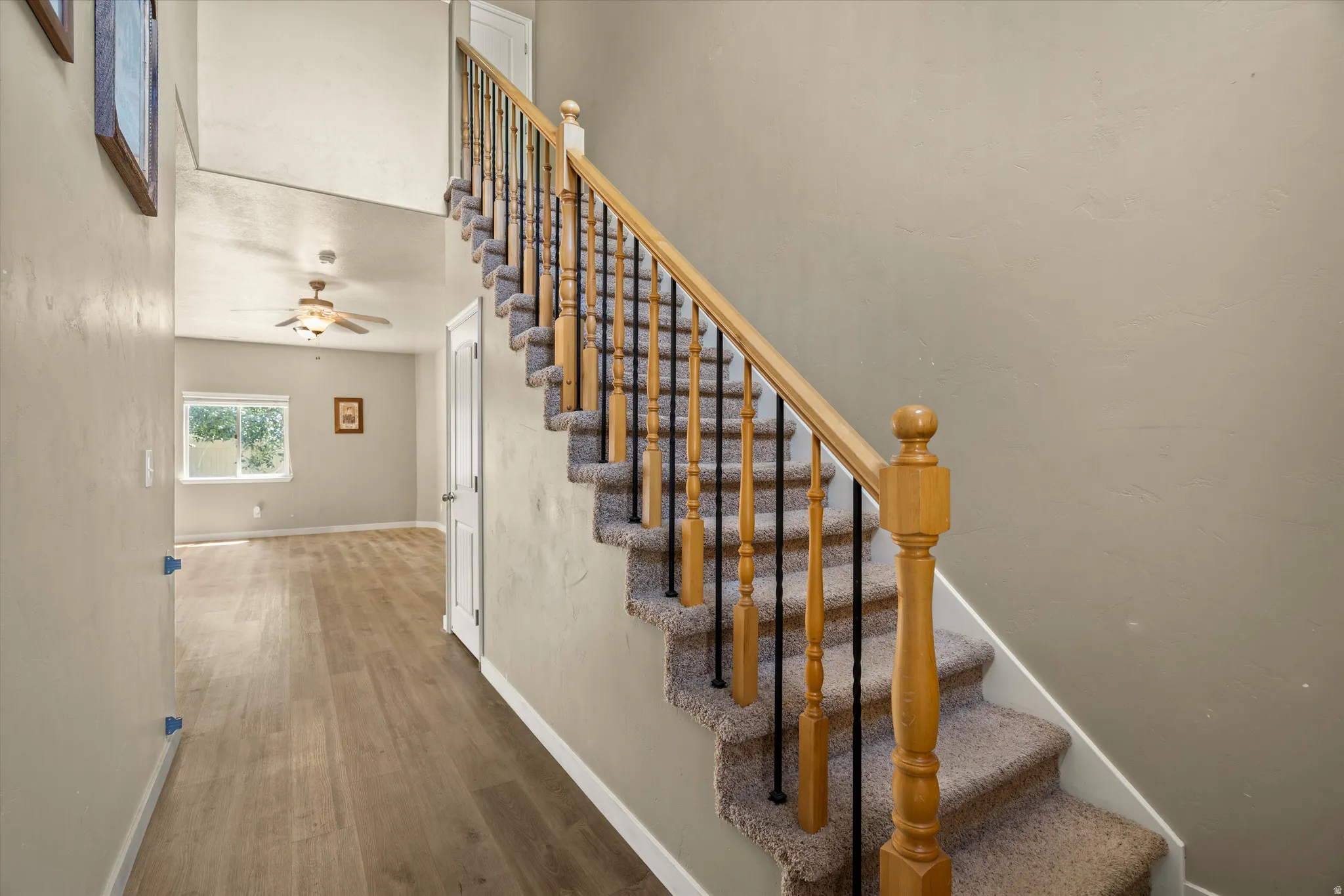 Carpeted staircase with wooden handrail and black metal balusters