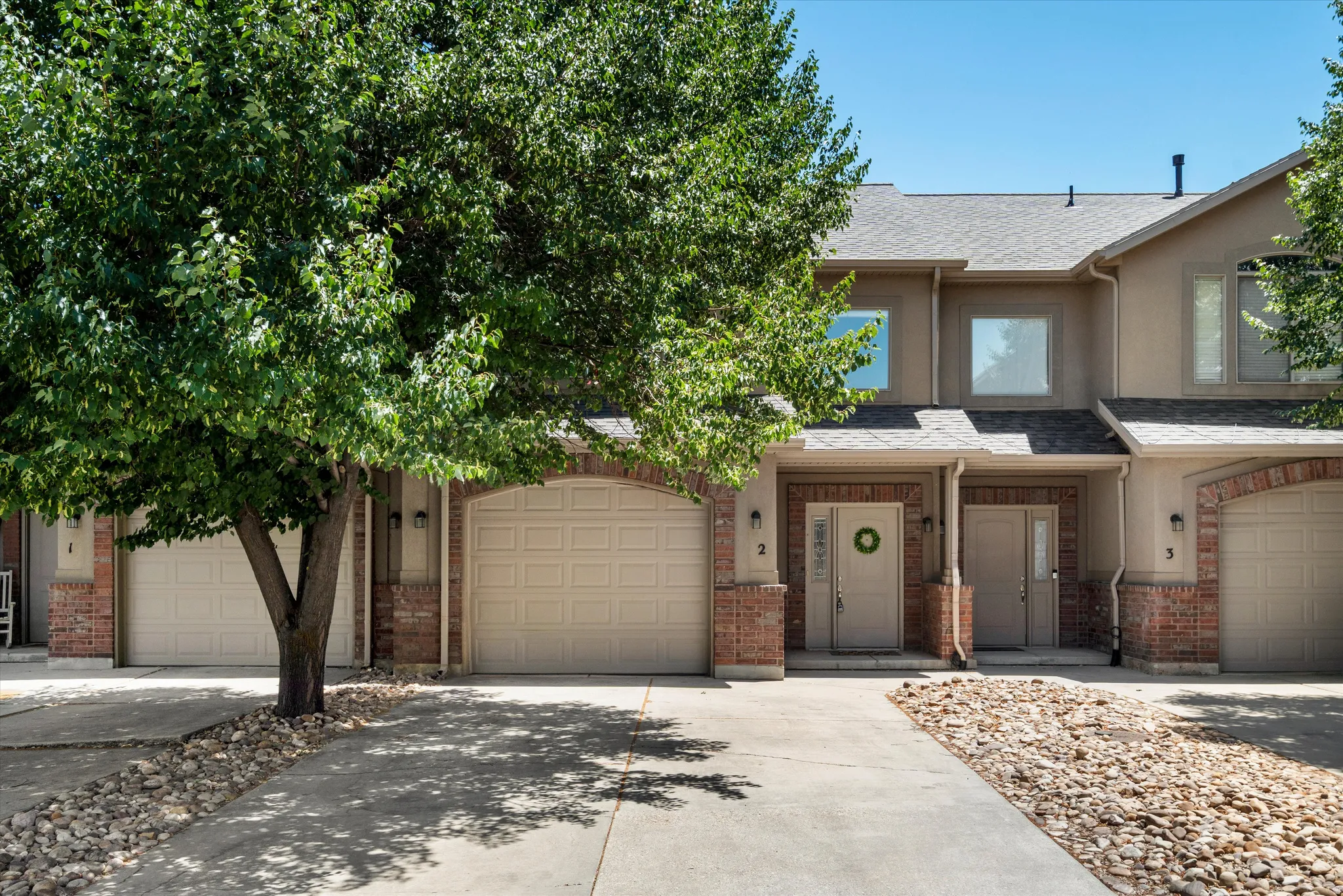 Exterior featuring a stucco finish with brick accents and arched garage doors