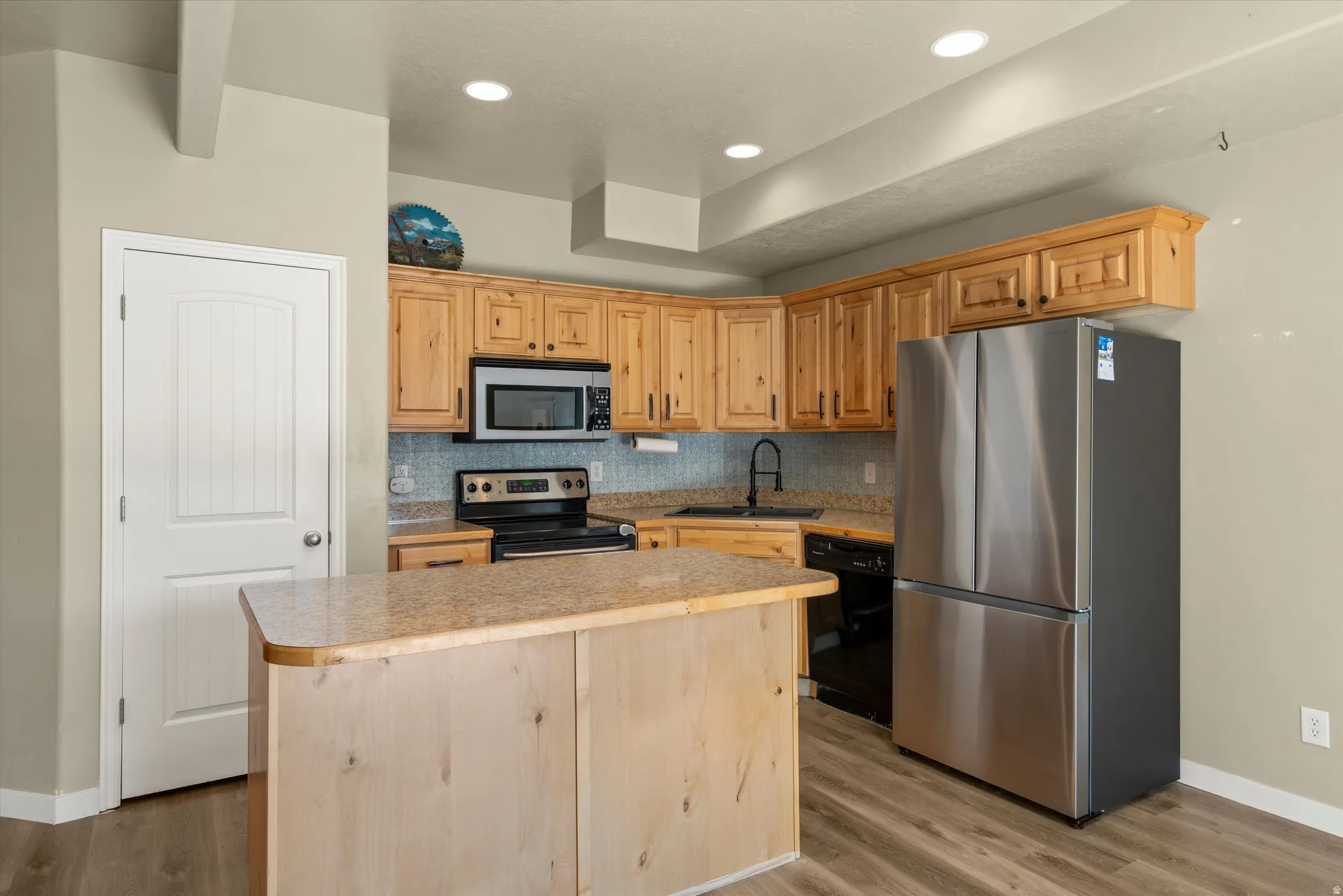 Kitchen featuring natural wood cabinetry, light-toned countertops, and a tile backsplash