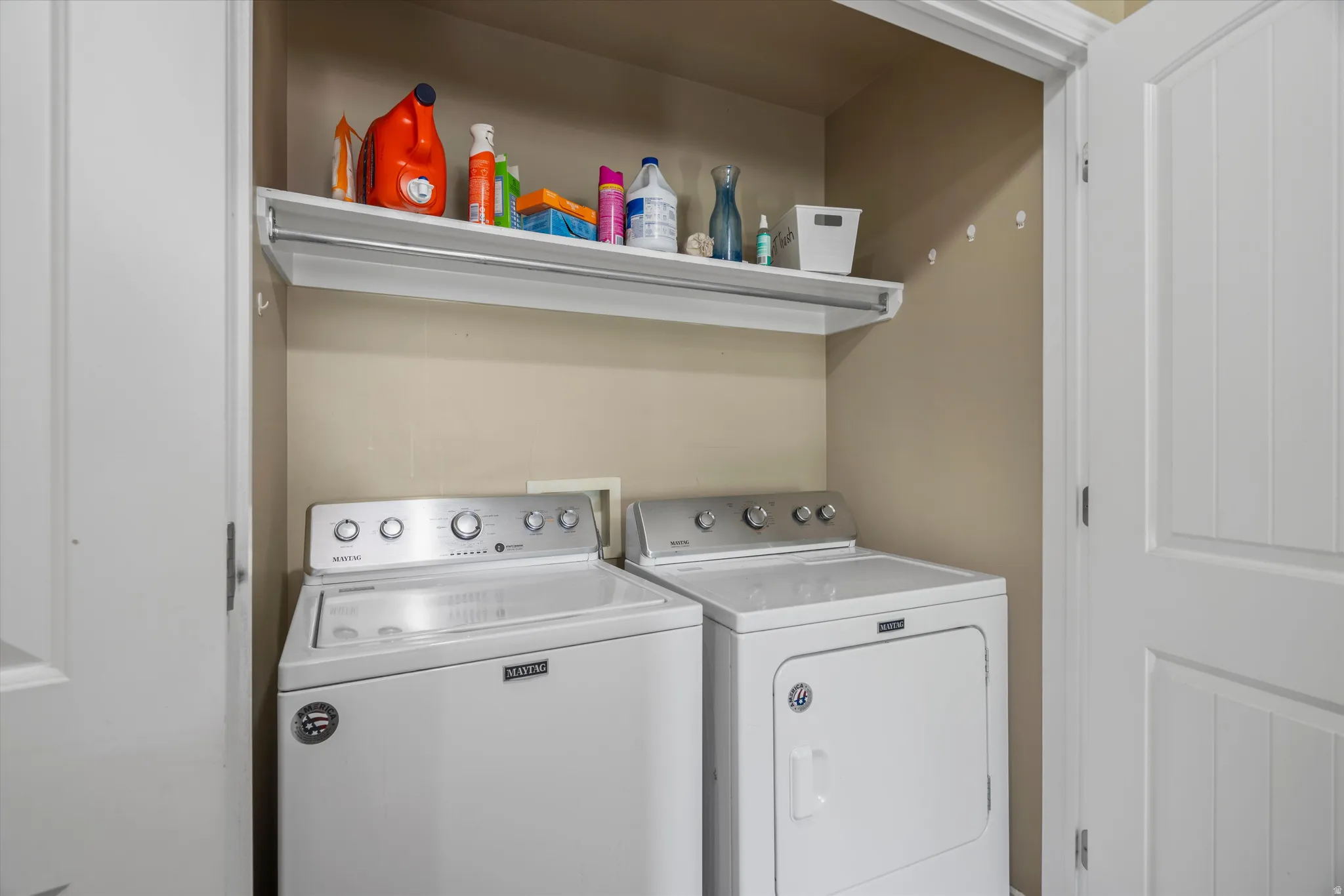 Dedicated laundry area featuring a white shelving unit, hanging rod, and light beige wall paint