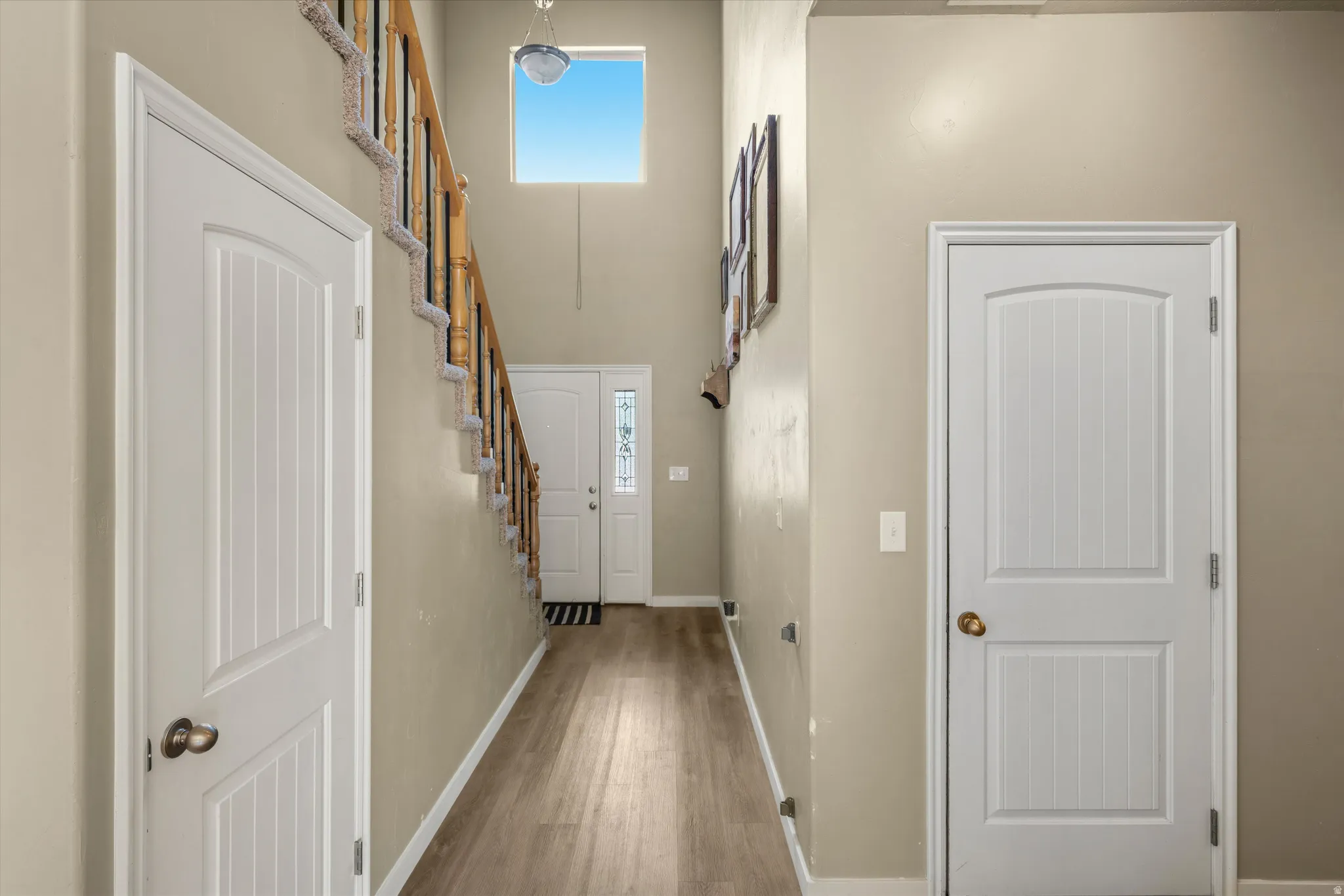 Two-story foyer featuring wood-finish flooring, a carpeted staircase with a wood handrail, and a high-set window