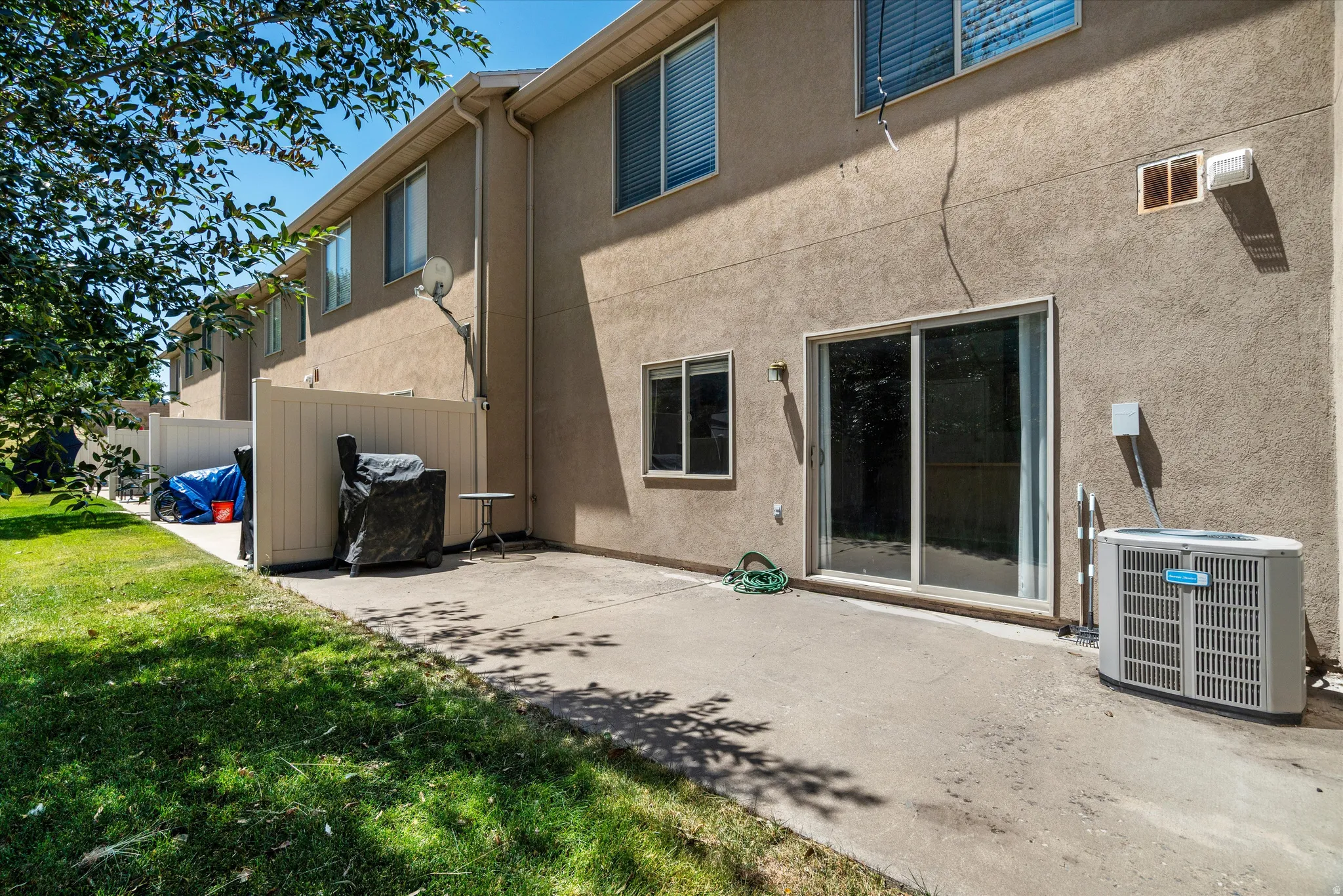 Private patio with concrete surfacing, adjacent to a manicured lawn area