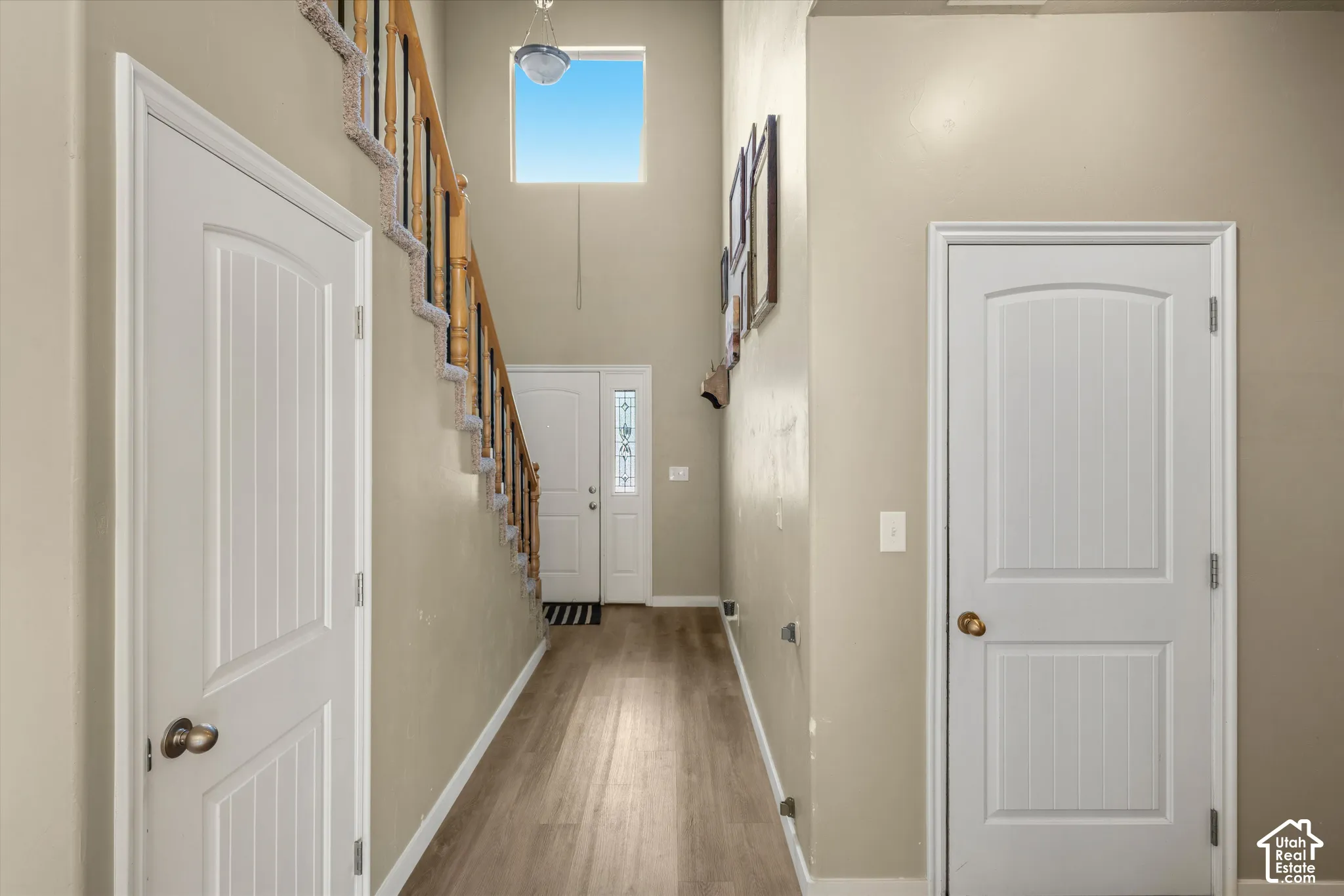 Two-story foyer featuring wood-finish flooring, a carpeted staircase with a wood handrail, and a high-set window
