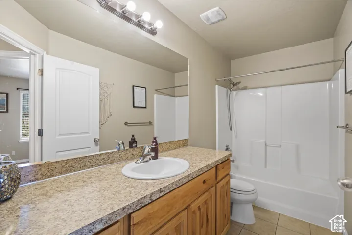 Full bathroom featuring a single vanity with a solid surface countertop, an undermount sink, and wood-finish cabinetry