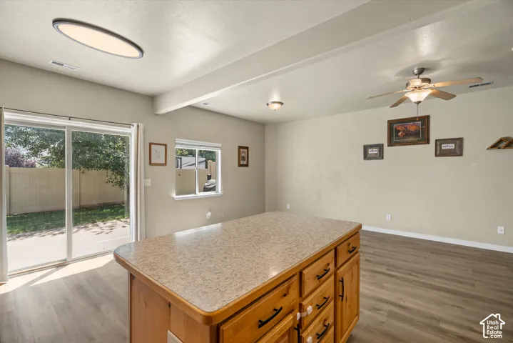 Kitchen island with a laminate countertop, wood-finish cabinetry, and black hardware