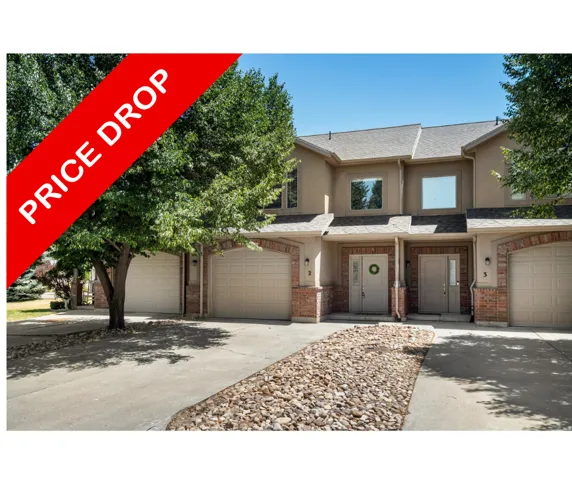 Exterior featuring stucco siding, brick accents, arched garage doors, and mature trees