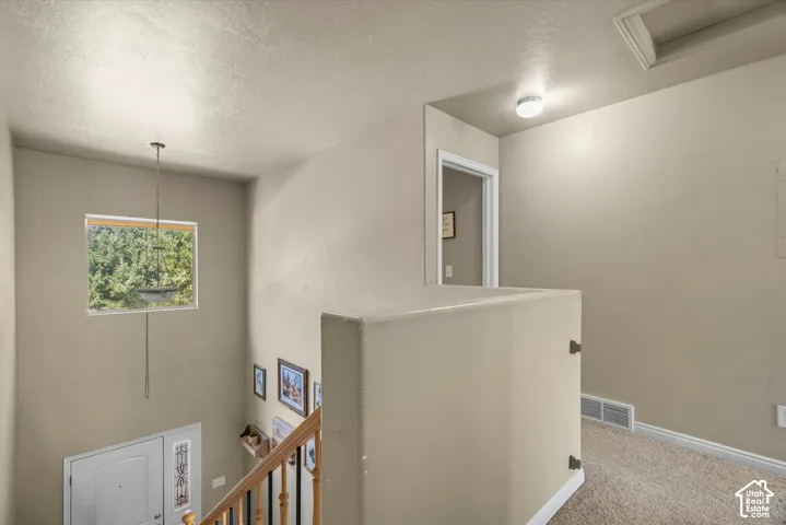 Two-story entryway featuring a decorative light fixture and a window with natural light