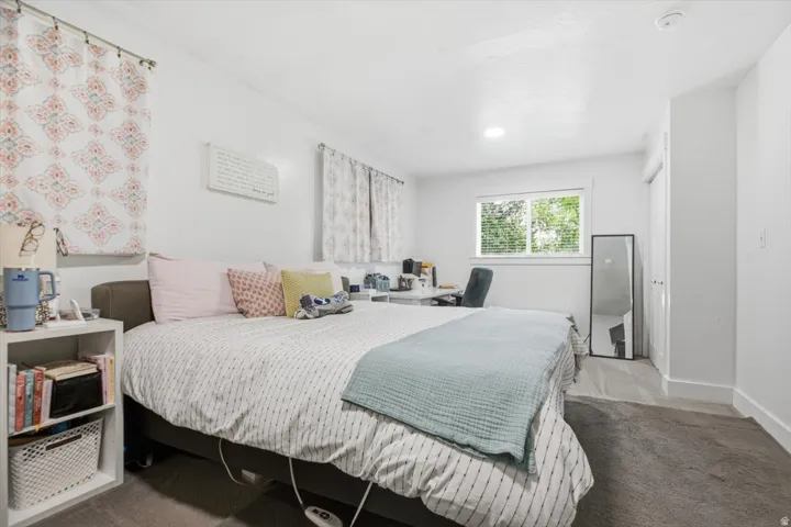 Carpeted bedroom featuring white walls, a large window, recessed lighting, and a closet with a white bi-fold door