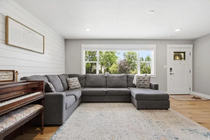 Living area featuring light wood-finish flooring, white shiplap accent wall, recessed lighting, and a multi-pane front entry door
