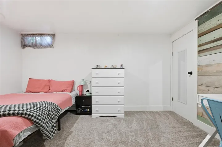 Carpeted room featuring a white door with frosted glass panel, baseboard trim, and a window with privacy covering