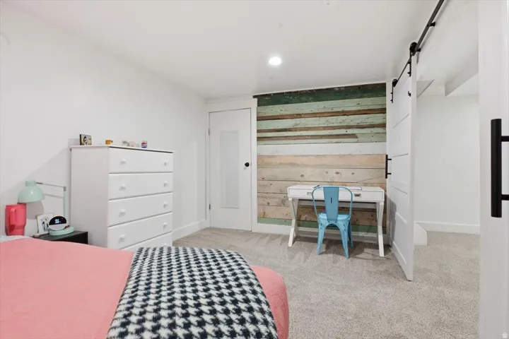 Accent wall featuring varied wood paneling, white walls, and light-colored carpeting