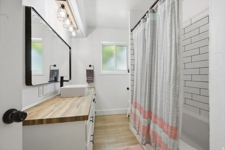 Bathroom featuring a butcher block vanity with a vessel sink, black faucet, and a large black-framed mirror