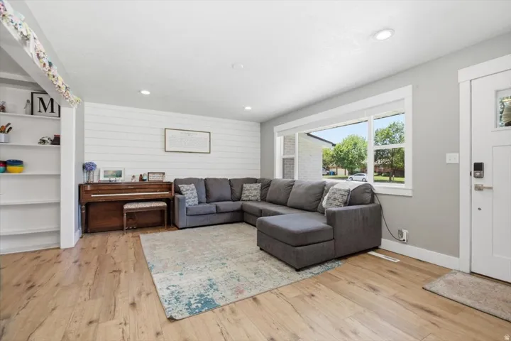 Bright living area featuring wood-finish flooring, a wide picture window, recessed lighting, and a prominent shiplap accent wall