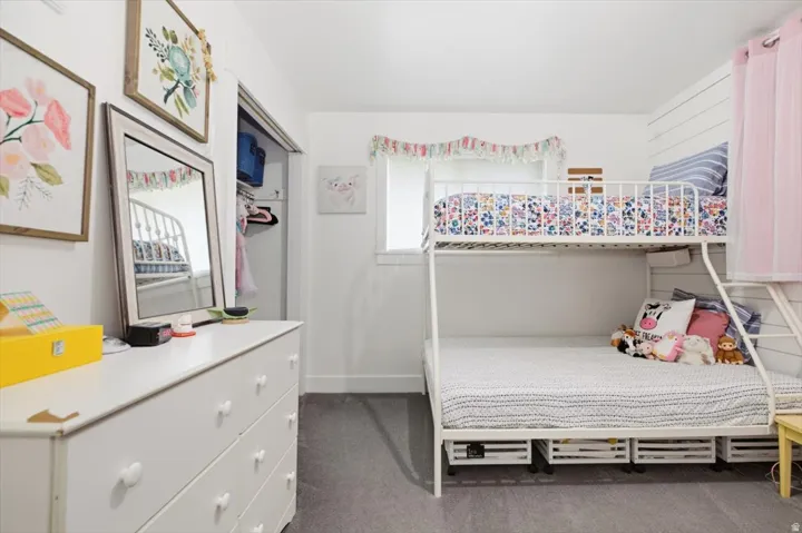 Bright interior room featuring white walls, gray carpet, a window with white trim, and a built-in closet