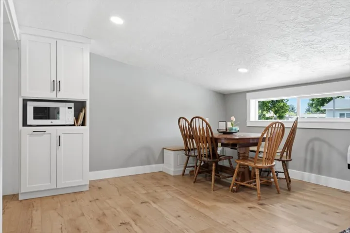 Dining area with wood-finish flooring, white built-in cabinetry, and recessed lighting