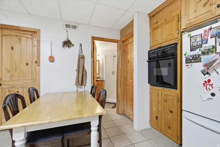 Kitchen area featuring light wood cabinetry, integrated wall oven, and tile flooring