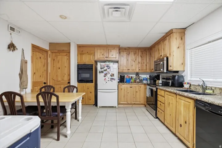 Kitchen featuring wood-finish cabinetry, granite-style countertops, stainless steel appliances, and tile flooring