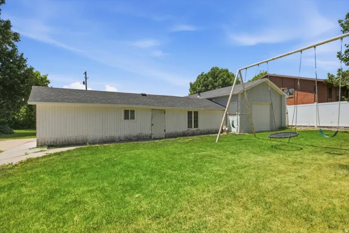 Expansive grassy yard with a detached structure featuring vertical siding and a shingled roof