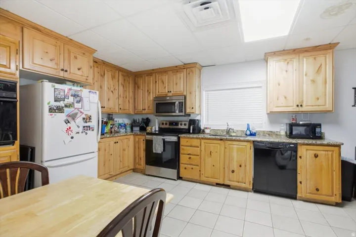 Kitchen featuring natural wood cabinetry, light-toned countertops, and tile flooring