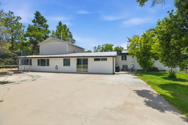Rear exterior featuring a concrete patio, white siding, and a metal roof