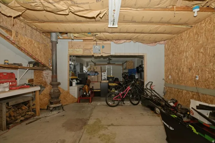 Unfinished utility space with OSB paneling, an exposed beam ceiling, concrete flooring, a support column, and built-in shelving