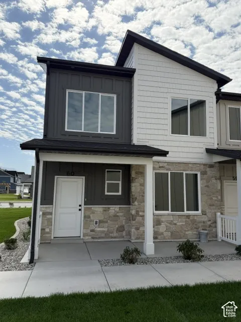 Modern townhome exterior featuring stone accents, white siding, and dark vertical paneling