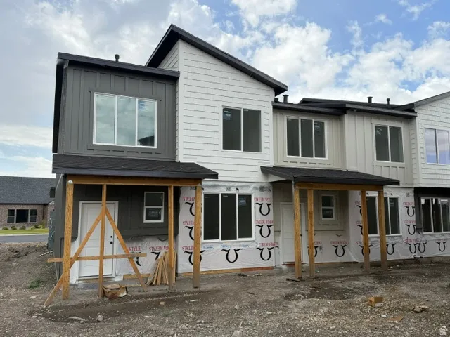 Modern multi-unit residence featuring contrasting vertical and horizontal siding, dark rooflines, and multiple windows