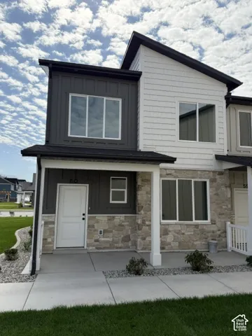 Modern townhome exterior featuring stone accents, white siding, and dark vertical paneling