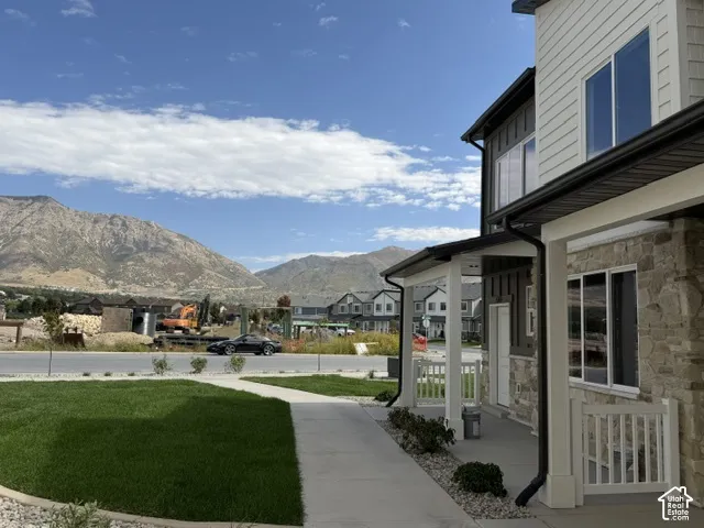 Stone facade, covered porch, large windows, mountain backdrop, manicured lawn