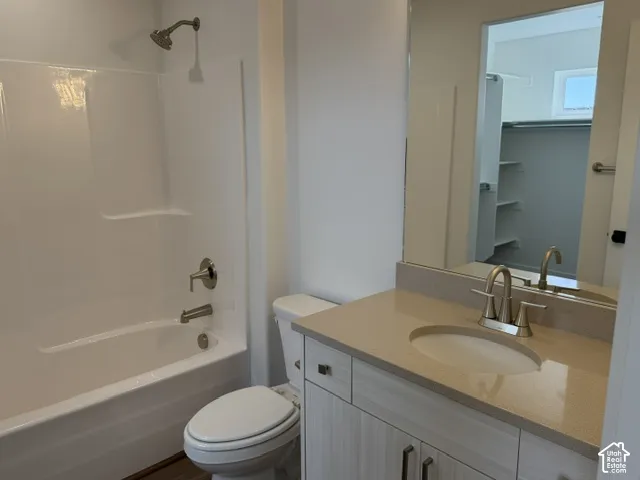 Bathroom featuring a full vanity with an integrated sink, a large mirror, and a full bathtub with an overhead shower
