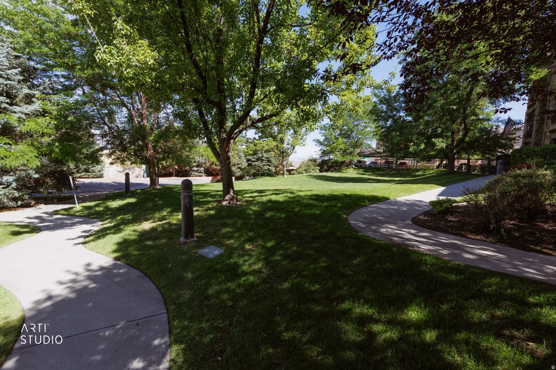 Manicured green space featuring mature trees, paved walking paths, and integrated bollard lighting