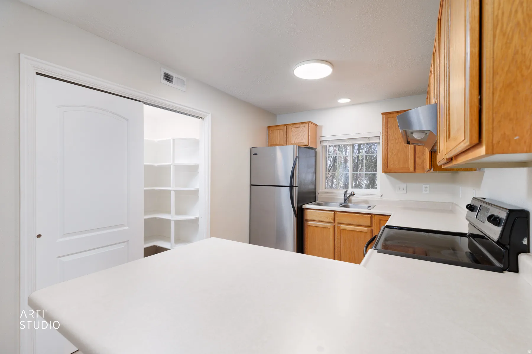 Kitchen featuring wood cabinetry, solid surface countertops, stainless steel appliances, and a built-in pantry with shelving