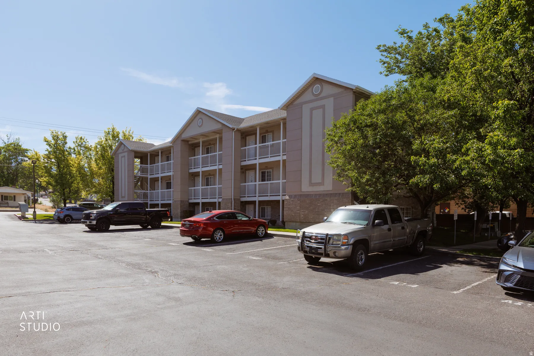 Multi-story building featuring light-toned exterior siding and private balconies with white railings