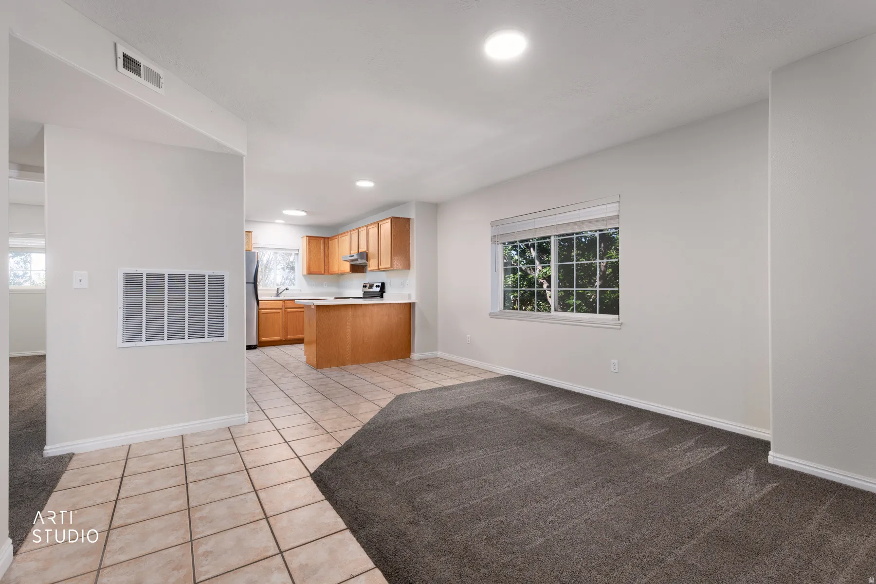 Expansive room featuring a blend of carpet and tiled flooring, recessed lighting, and a large window
