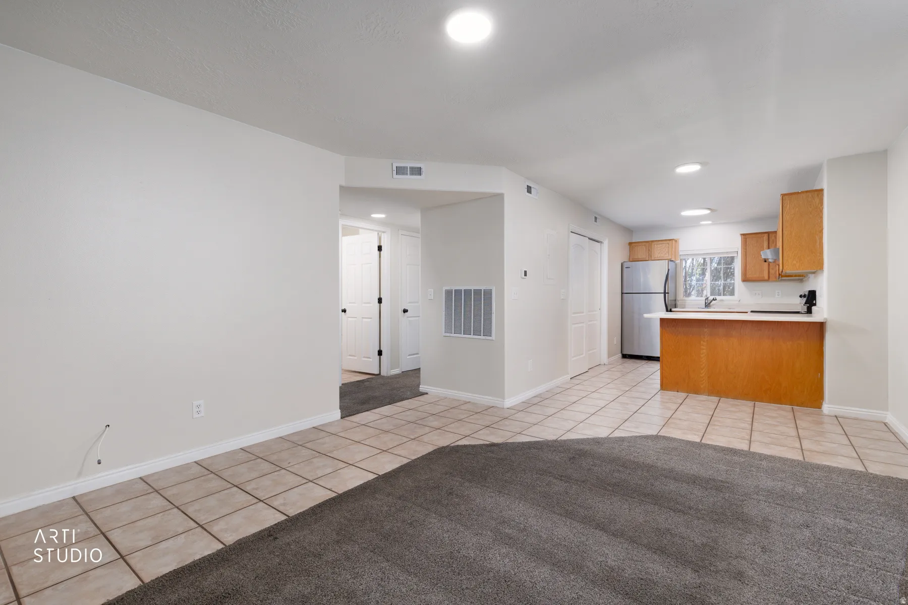 Kitchen with light wood cabinetry, white countertops, and stainless steel refrigerator