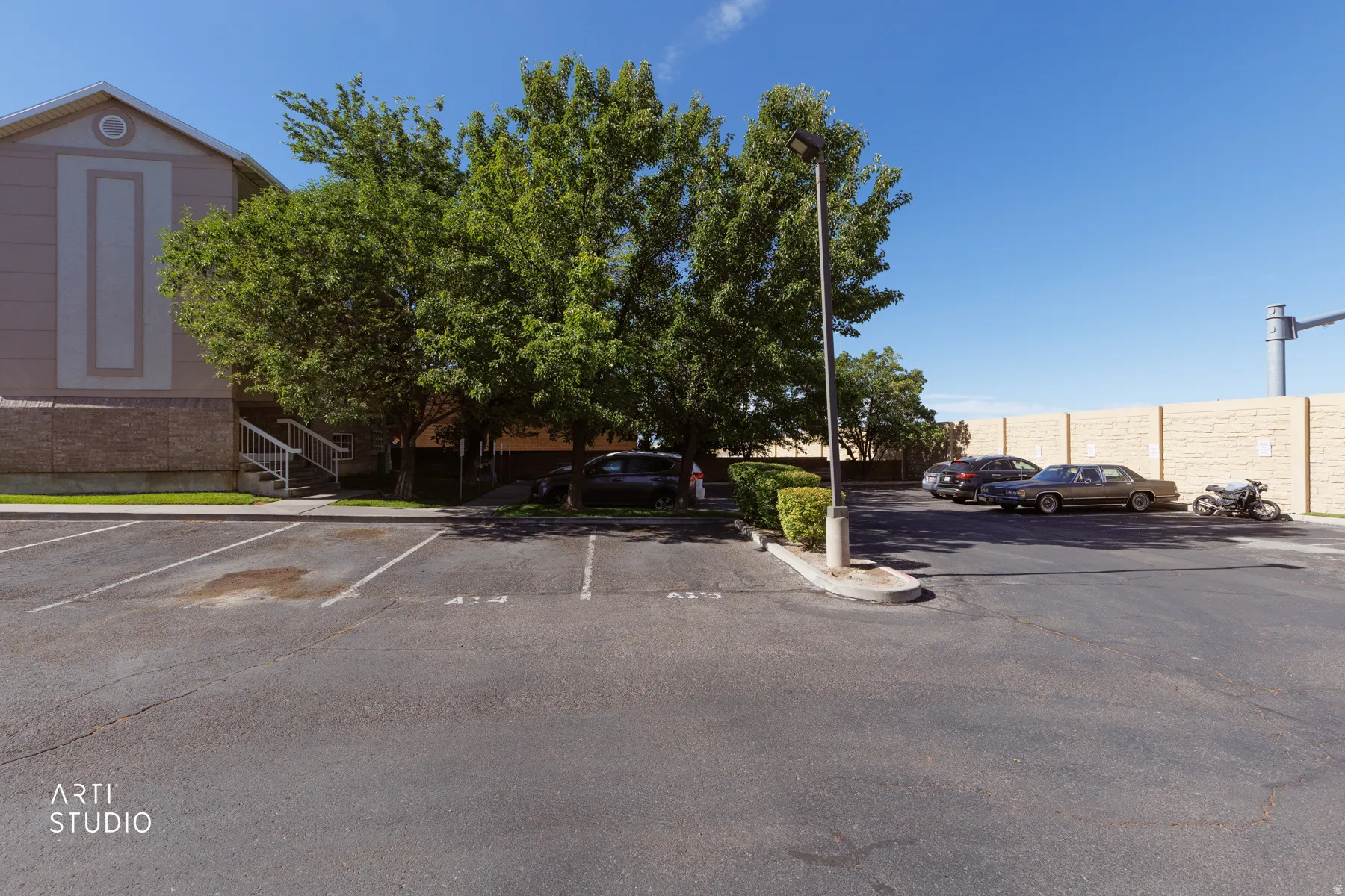 Paved parking area with marked spaces, bordered by a multi-story building featuring a stucco and brick exterior