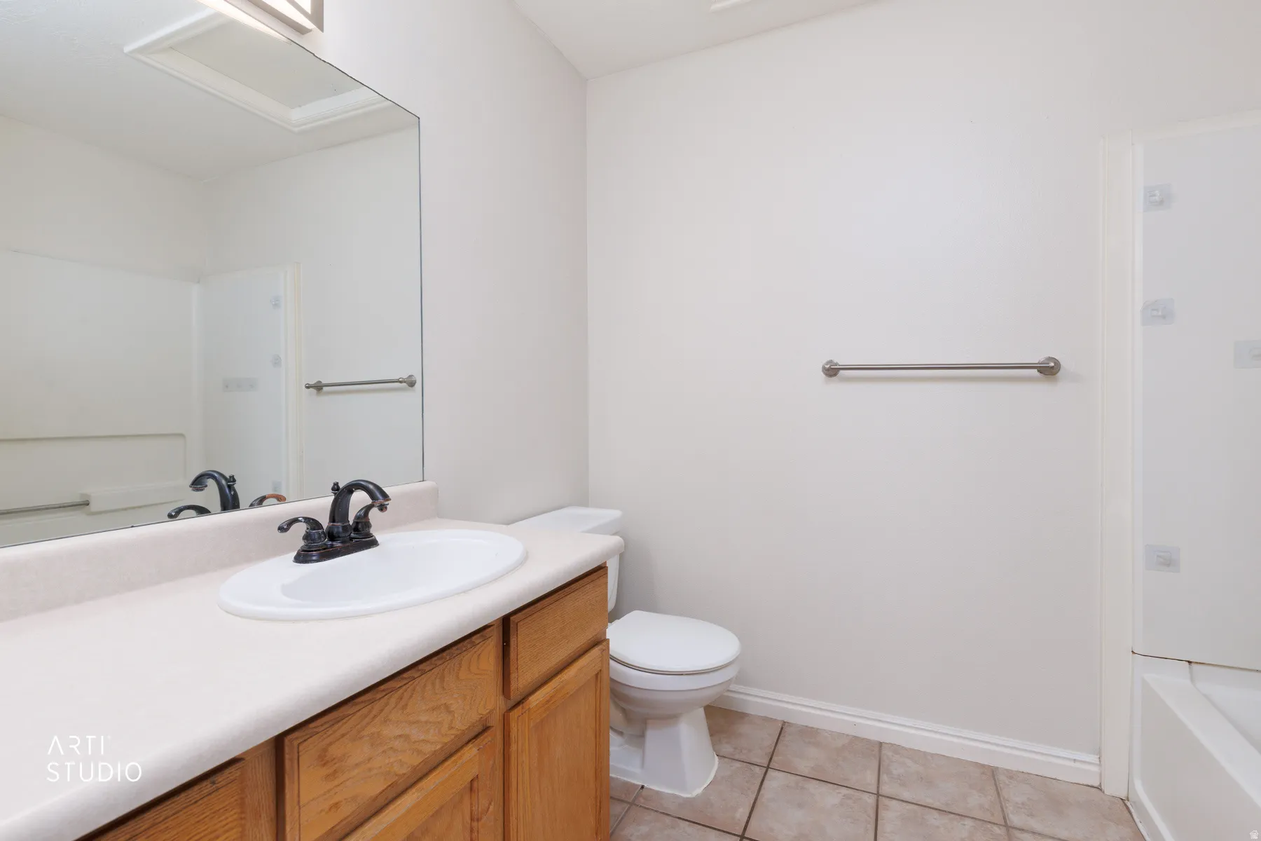 Bathroom vanity with a white oval sink, dark bronze faucet, and light-toned countertop
